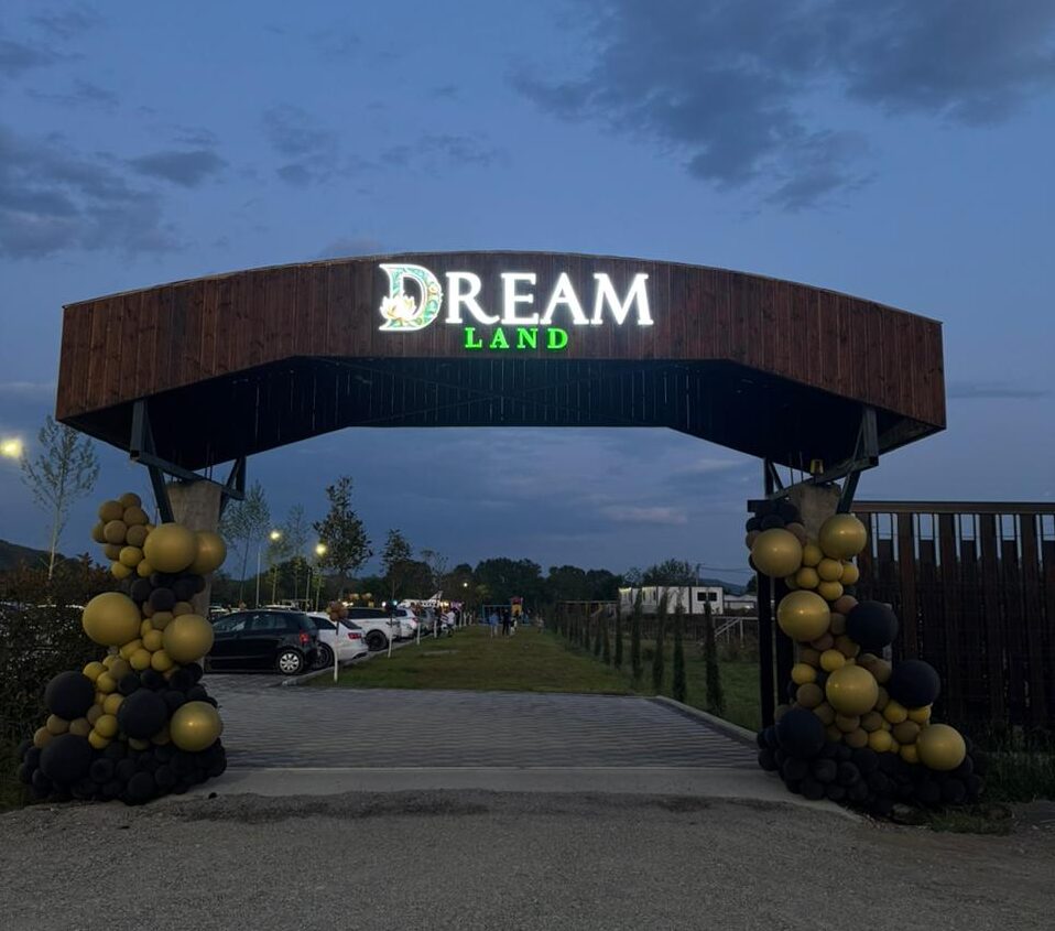 Panoramic view of Dream Land camping in Shkoder, with tents and campervans on the grassy bank of the Buna River.